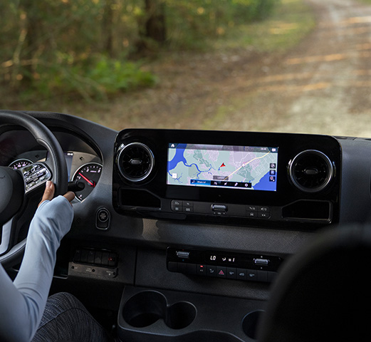 A Mercedes-Benz Cargo Van parked by a lake and using the Mercedes me connect feature. 