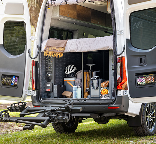 A Mercedes-Benz Cargo Van parked with the rear doors open showcasing the camper van cargo space.